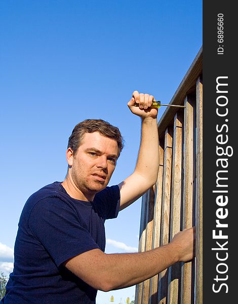 Angry man using screwdriver to fix porch. Vertically framed photo. Angry man using screwdriver to fix porch. Vertically framed photo.