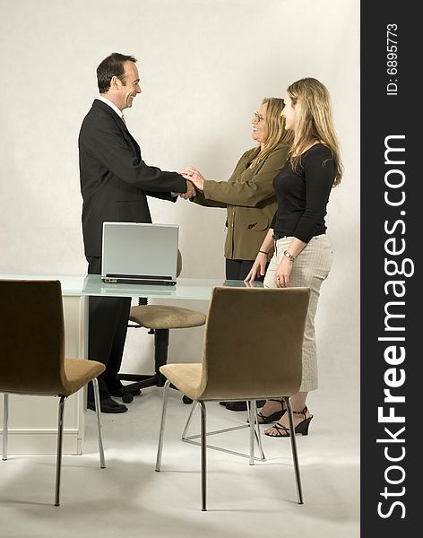 Three people are in a business meeting. They are smiling at each other and shaking hands. Vertically framed shot. Three people are in a business meeting. They are smiling at each other and shaking hands. Vertically framed shot.
