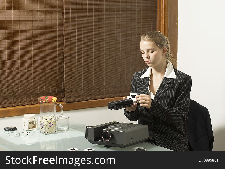 Woman  places slides in  a slide show projector. There is a pitcher of lemonade and a candle nearby. Horizontally framed photo. Woman  places slides in  a slide show projector. There is a pitcher of lemonade and a candle nearby. Horizontally framed photo.
