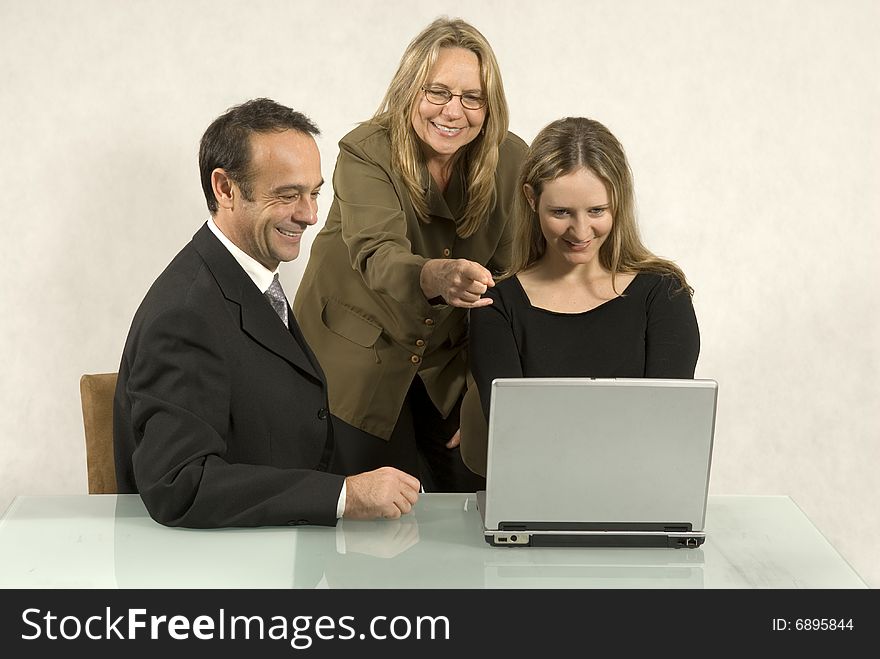 Three people are in a business meeting. They are smiling and looking at the screen of the laptop. Horizontally framed shot. Three people are in a business meeting. They are smiling and looking at the screen of the laptop. Horizontally framed shot.