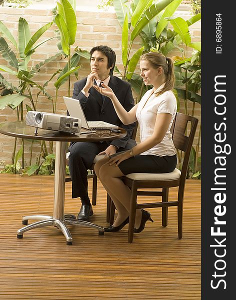 Man and woman with a projector and a laptop. They are seated and smiling . Vertically framed photo. Man and woman with a projector and a laptop. They are seated and smiling . Vertically framed photo.