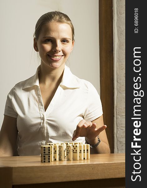 Smiling young woman seated at desk playing dominos. Vertically framed photo. Smiling young woman seated at desk playing dominos. Vertically framed photo.