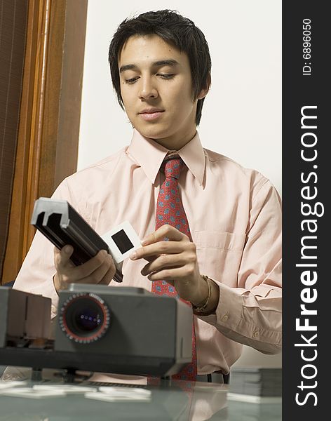 Man wearing a serious expression on his face as he looks at a slide next to a projector. Vertically framed photo. Man wearing a serious expression on his face as he looks at a slide next to a projector. Vertically framed photo.