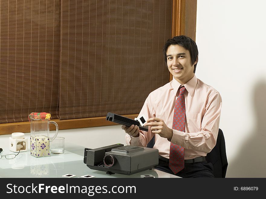 Man smiling as he puts slides in a slide show projector. Horizontally framed photo. Man smiling as he puts slides in a slide show projector. Horizontally framed photo.