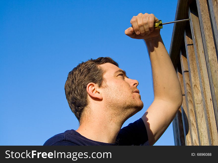 Man using screwdriver to fix porch. Horizontally framed photo. Man using screwdriver to fix porch. Horizontally framed photo.