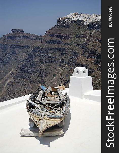 A very old non-used boat on the top of a greek building with beautiful view on caldera of Santorini. A very old non-used boat on the top of a greek building with beautiful view on caldera of Santorini.