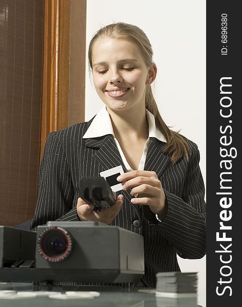 Woman  smiling as she places slides in  a slide show projector. Vertically framed photo. Woman  smiling as she places slides in  a slide show projector. Vertically framed photo.