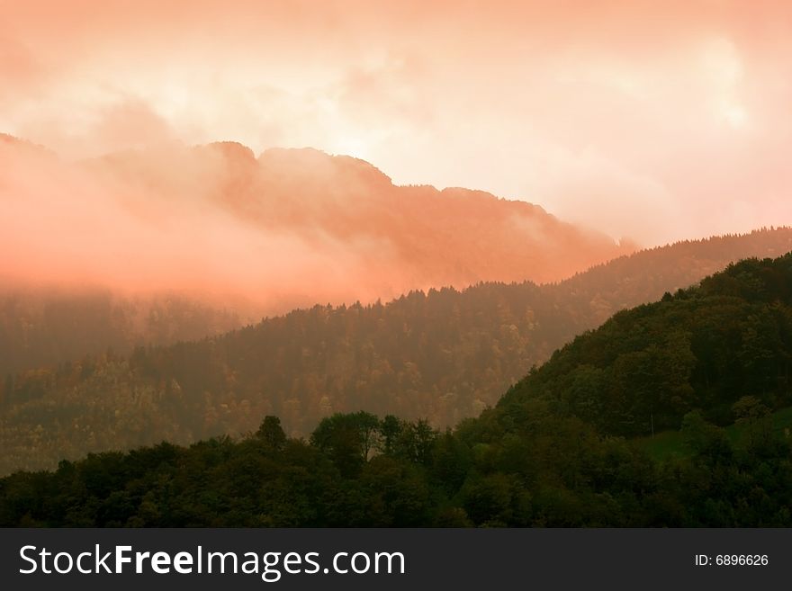 Misty and cloudy mountains silhouette with sunset pink skies. Misty and cloudy mountains silhouette with sunset pink skies
