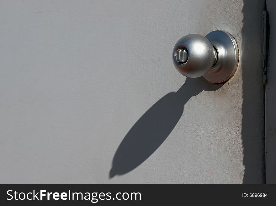Grungy looking grey metal door with doorknob in bright sunshine