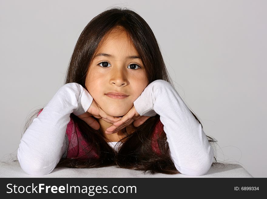 Cute young hispanic girl with her head propped up in her hands