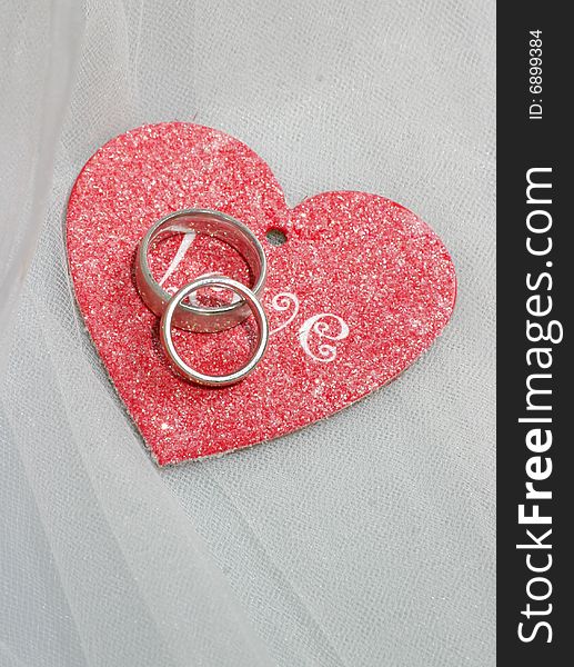 Wedding bands on a red heart with the word love inscribed. Wedding bands on a red heart with the word love inscribed