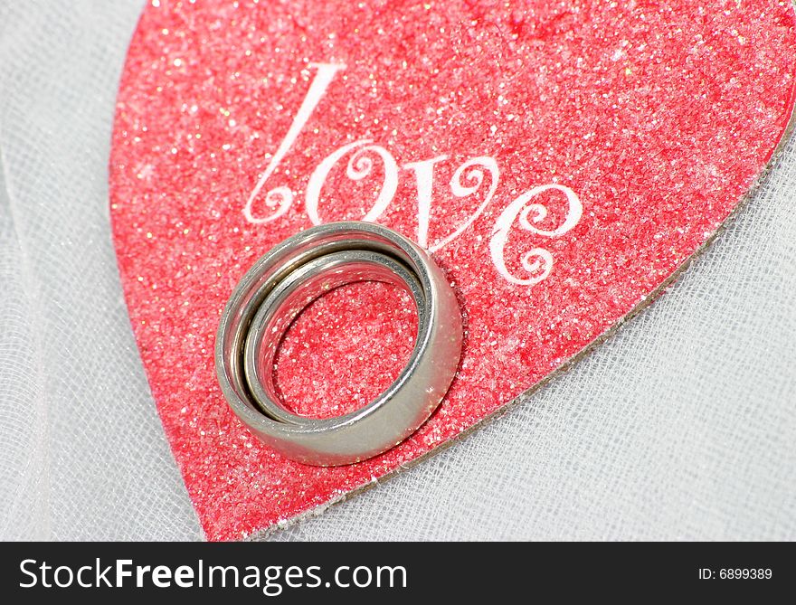 Wedding bands nested on top of a red heart saying love