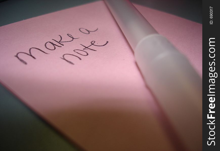 A pink Post-It Note with an ink pen laying on top. A pink Post-It Note with an ink pen laying on top.