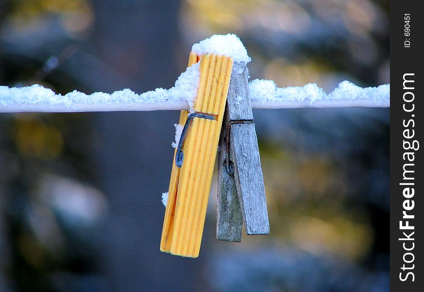 Two snowy clothes-pins on a line. Two snowy clothes-pins on a line