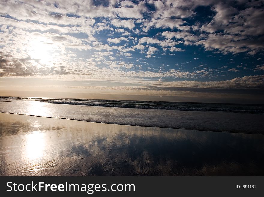 An expansive beach with small waves and a dramatic deep blue sky with clouds. An expansive beach with small waves and a dramatic deep blue sky with clouds