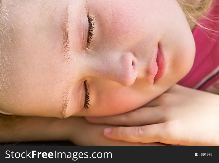 Close-up of a beautiful young girl sleeping and dreaming outside in the garden. Close-up of a beautiful young girl sleeping and dreaming outside in the garden