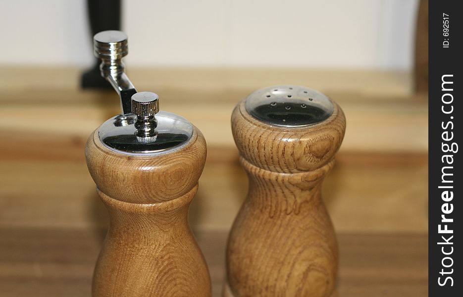 Wooden pepper mill and salt shaker (focus on pepper mill). Wooden pepper mill and salt shaker (focus on pepper mill).