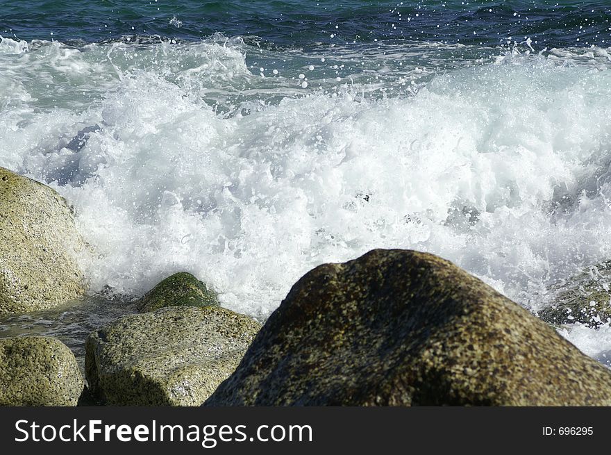 Waves racing to shore and breaking at the rock formation. Waves racing to shore and breaking at the rock formation