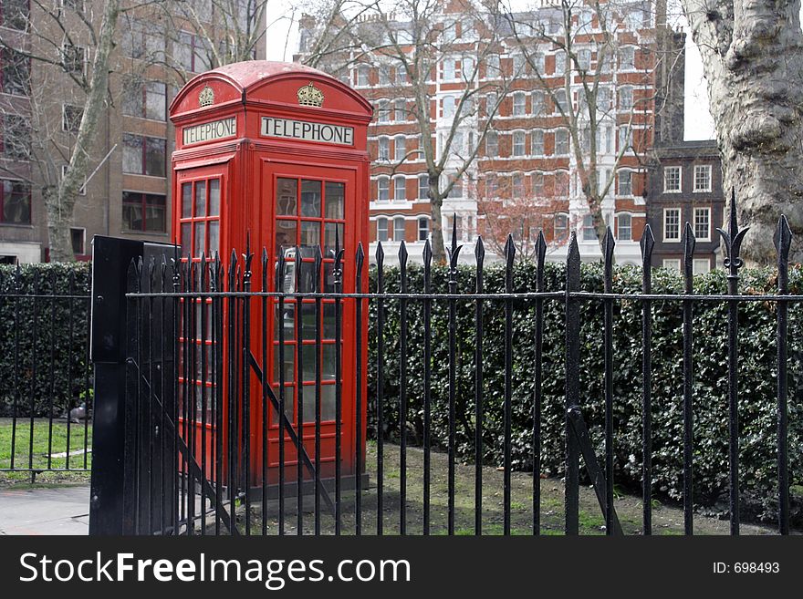A traditional london phone box behind railings. A traditional london phone box behind railings
