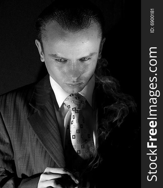 Young man in suit smoking cigarette looking down. Young man in suit smoking cigarette looking down