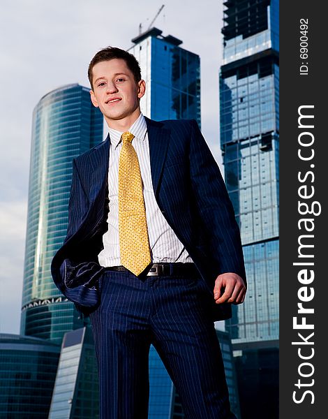 Friendly businessman standing against skyscraper