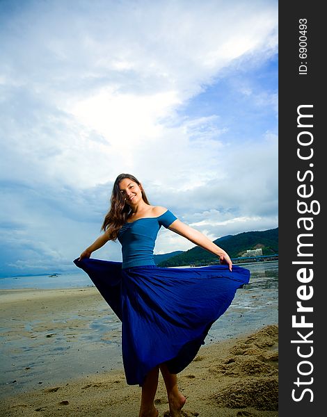 Young eurasian woman at the sunset beach turn and flipping her skirt