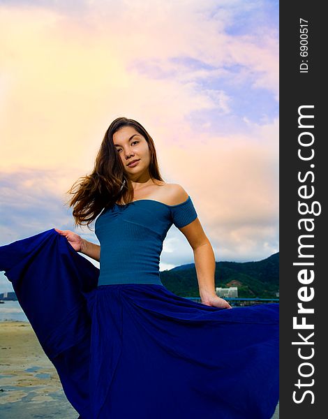 Young Eurasian woman flipping her skirt on the sunset beach