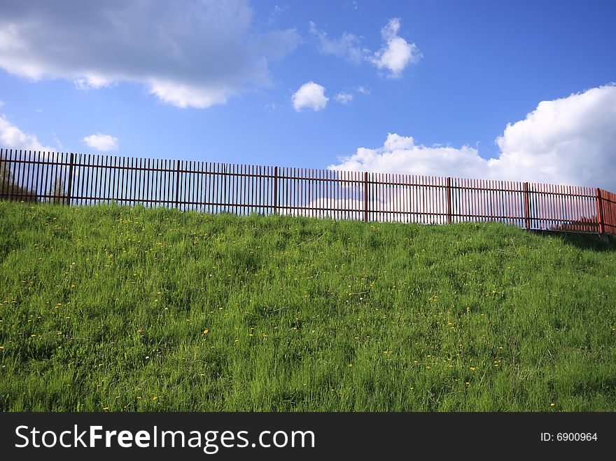 Fence on the grassy hill with cloudy sky in background. Fence on the grassy hill with cloudy sky in background.