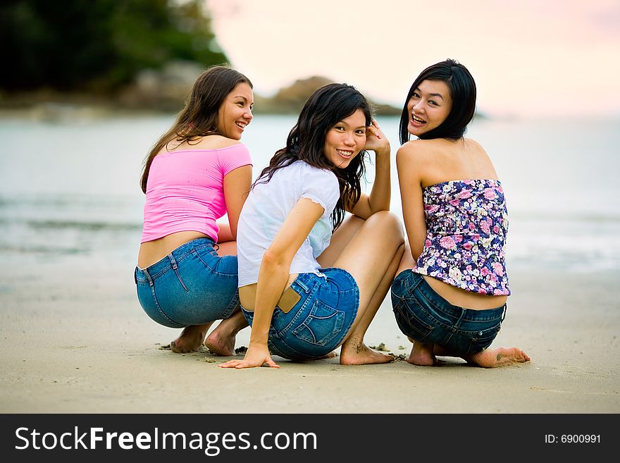 Group of happy asian woman friends squatting by the sunset beach. Group of happy asian woman friends squatting by the sunset beach