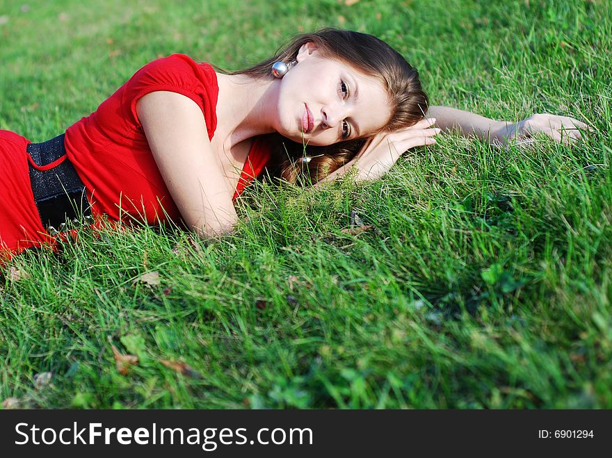 Beautiful young woman in red lying on the green grass. Beautiful young woman in red lying on the green grass