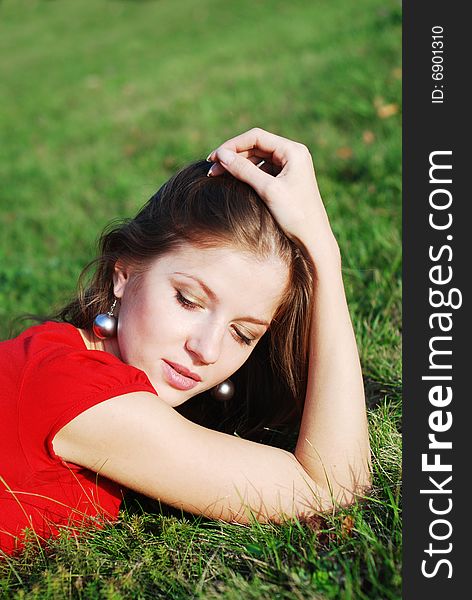 Beautiful young woman in red lying on the green grass. Beautiful young woman in red lying on the green grass
