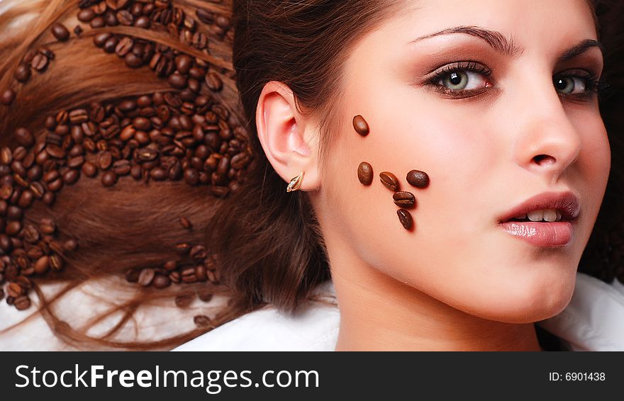 Coffee beans on the hair and face of beautiful young woman. Coffee beans on the hair and face of beautiful young woman