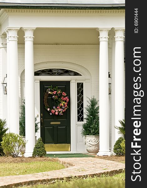 A black door with a wreath graced with columns. A black door with a wreath graced with columns.