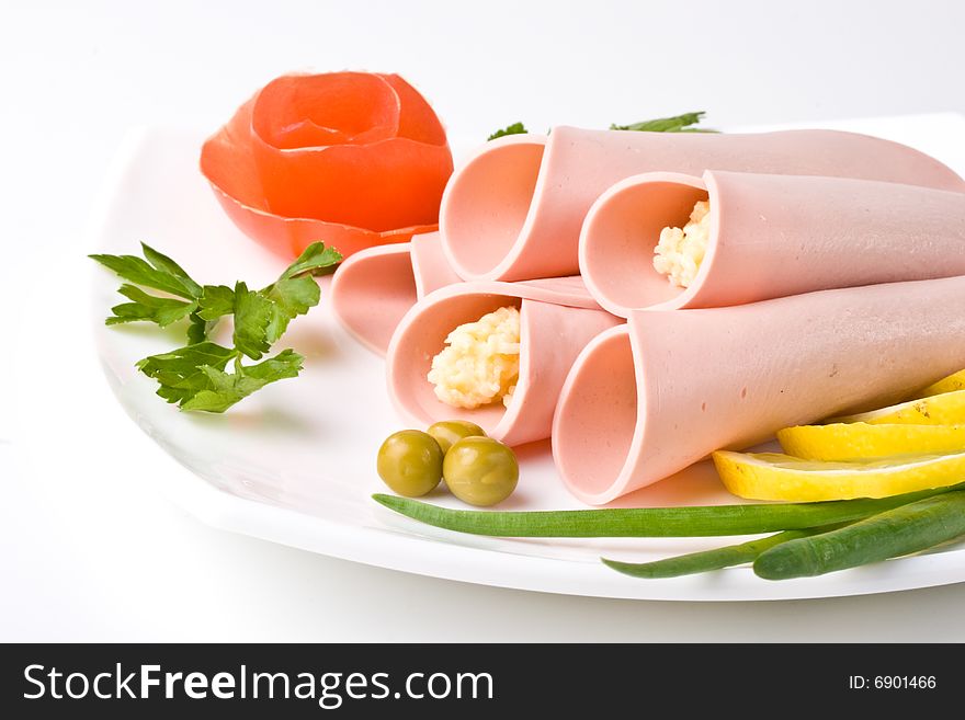 Rolls from sausage and cheese with vegetables on a white background