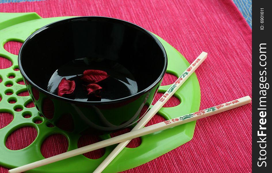 Black bowl and the Chinese sticks on a red-green background