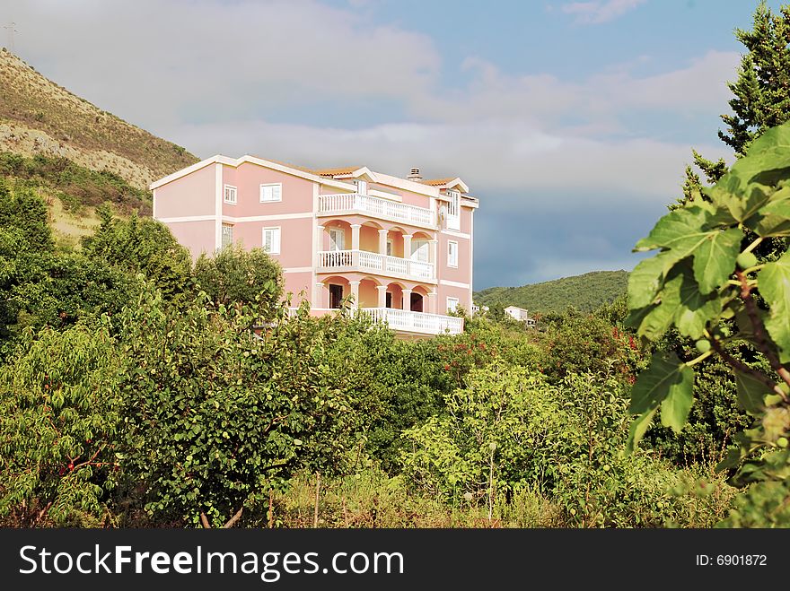 Pink house on hill surrounded by green trees