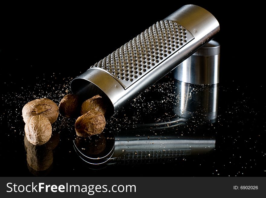 Nutmeg and silver grater on black background