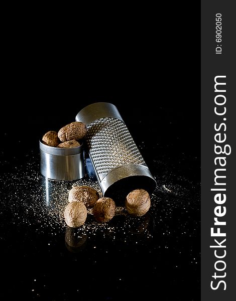 Nutmeg and silver grater on black background