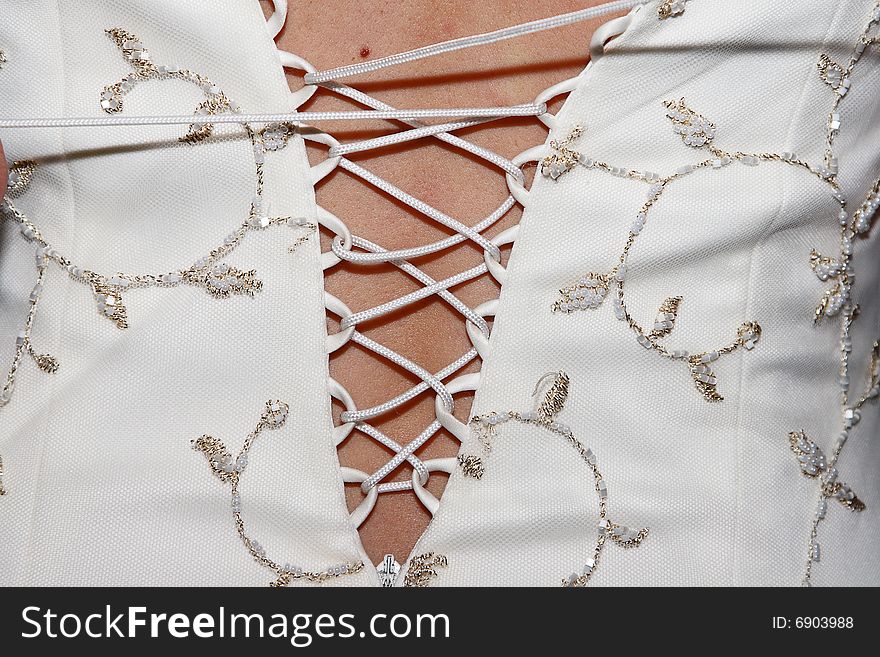 Close up of wedding gown bodice being laced up