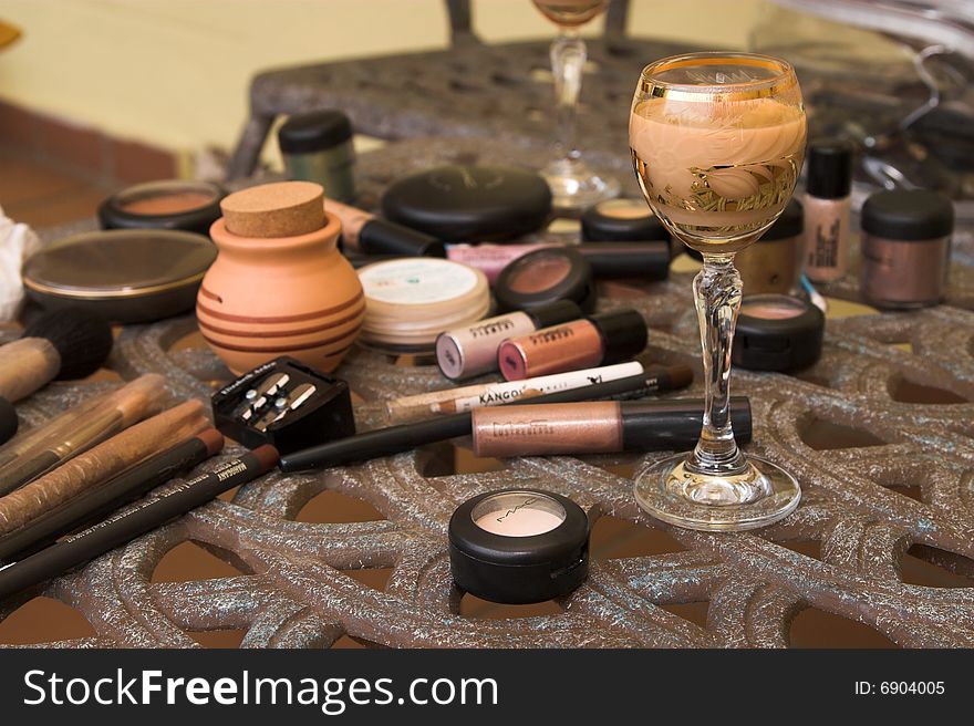 Various forms of make-up on a table with a drink