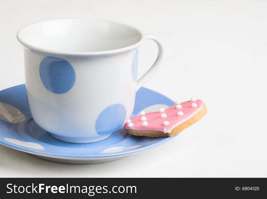 Pink polkadot, heart-shaped cookie on a blue cup. Pink polkadot, heart-shaped cookie on a blue cup