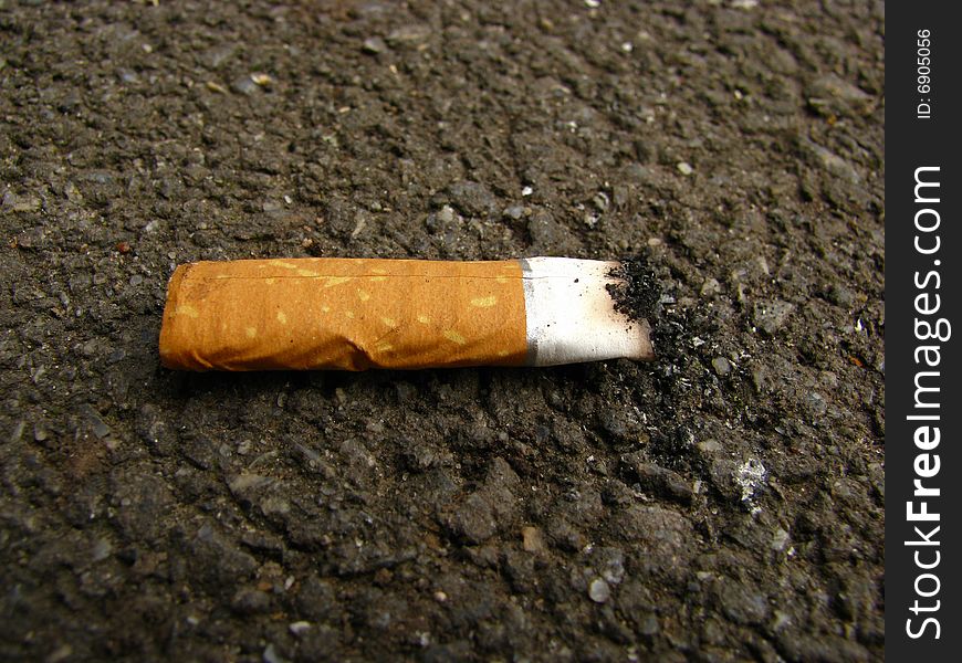 Cigarette-end trampled down feet on an asphalt