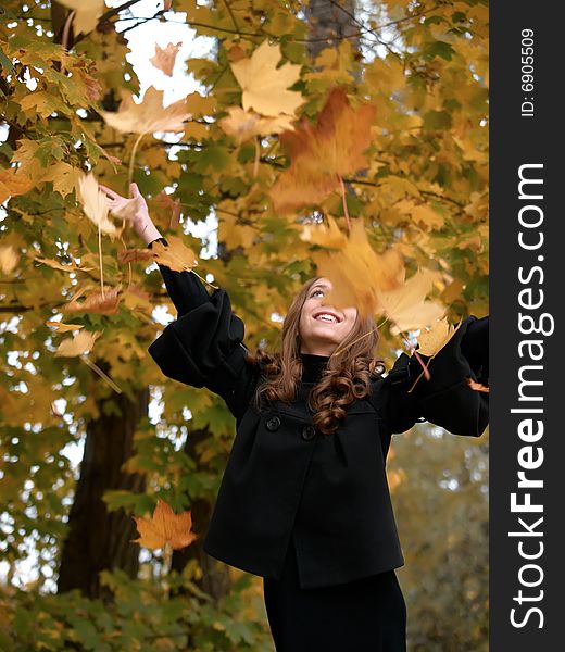 Youn Girl Throws Leaves Upwards In Forest.