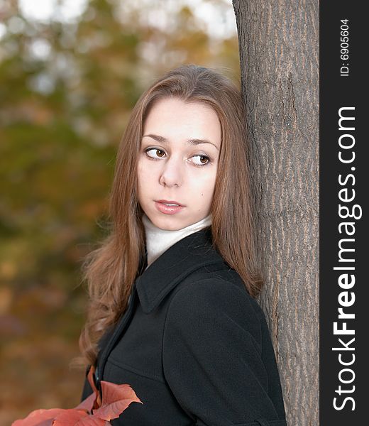 Young girl looks aside in autumn forest.