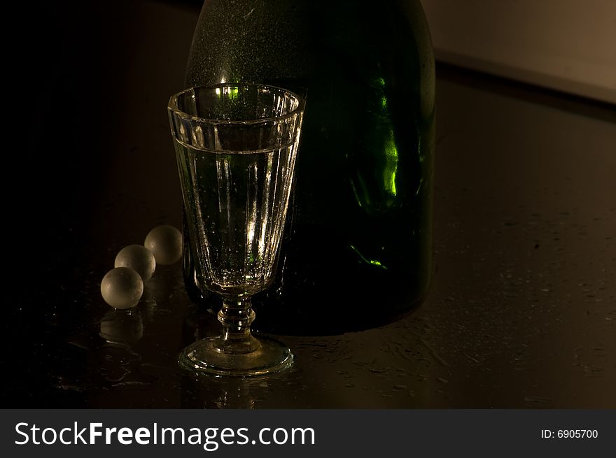 Glass with champagne and green bottle. Glass with champagne and green bottle
