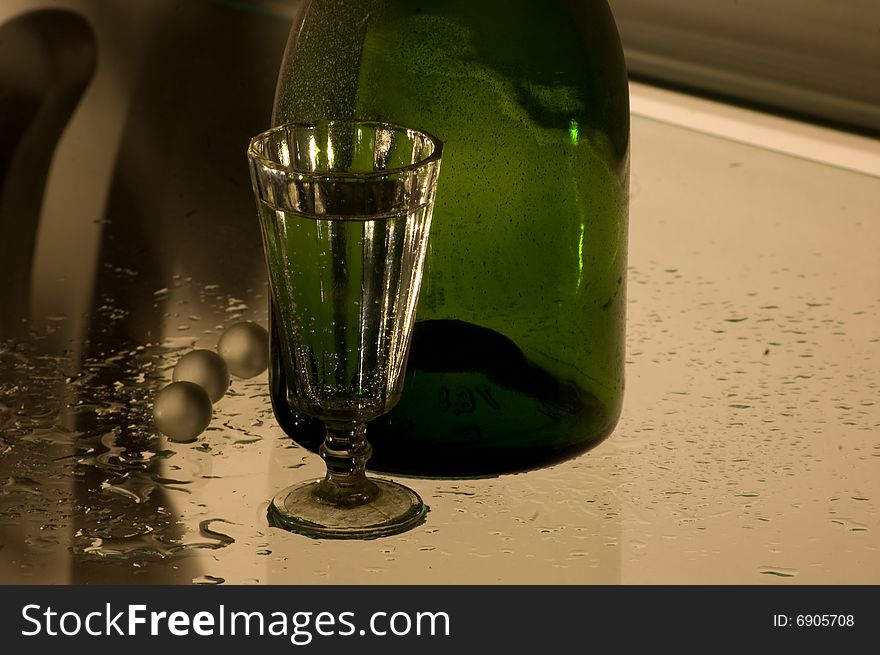 Glass with champagne and green bottle. Glass with champagne and green bottle