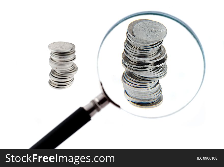 Magnifying glass with a two small columns of coins behind it. Magnifying glass with a two small columns of coins behind it.