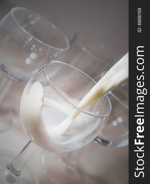 Fresh milk pouring into a round glass with selective focus on the milk showing its creamy texture