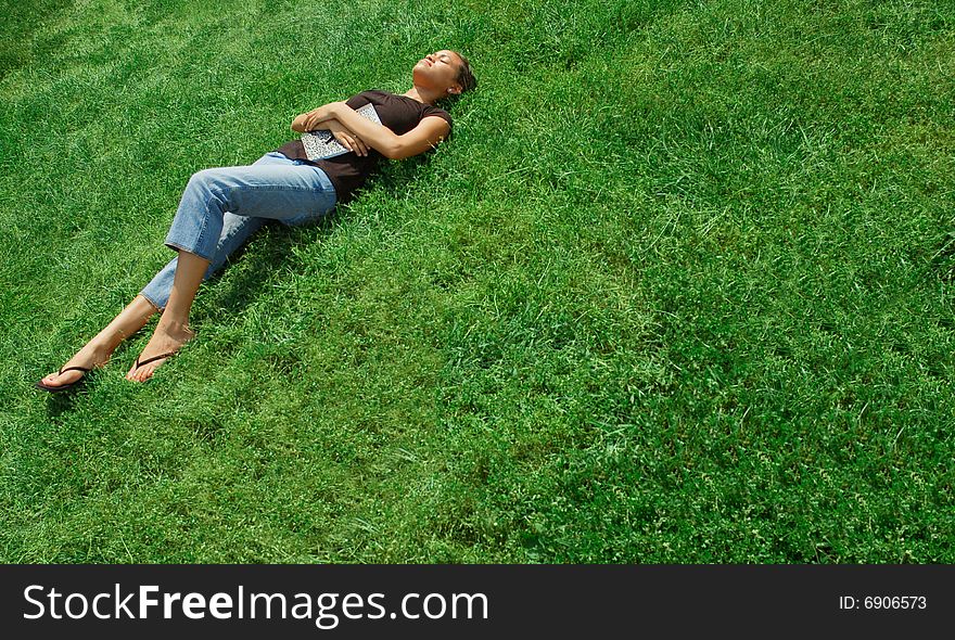 Beautiful young woman laying in green field with notebook. Beautiful young woman laying in green field with notebook.
