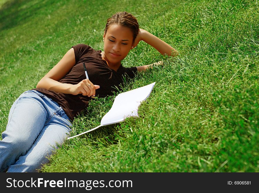 Beautiful young woman in green field with notebook. Beautiful young woman in green field with notebook.